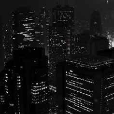 black and white cityscape at night with skyscrapers lit up in the distance