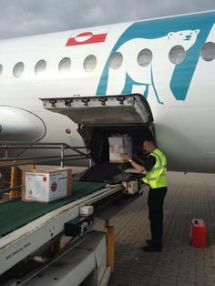 a man standing next to an airplane loading boxes