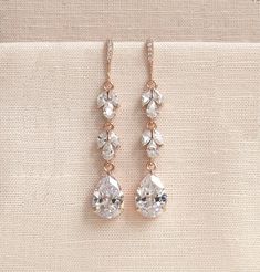 two pairs of earrings on a beige cloth