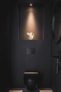 a black bathroom with a toilet, sink and mirror on the wall next to it