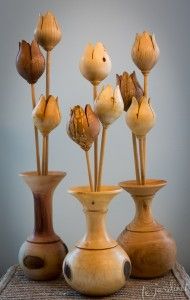 four vases with flowers in them on a table top, one is brown and the other is white