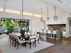 a large open concept kitchen and dining room with wood flooring, white walls and ceiling