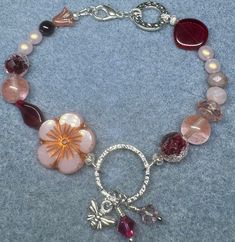 BLOSSOM & BEE BRACELET 8.5" This bracelet was designed and made by me. It has faceted crystals, glass, and fire-polished Czech beads and features a large pink flower.  Two pink semi-precious stones called Fluorite and a small red Garnet bead are on the bracelet as well.  The Bee Charm, metal parts and silver wire are silver-plated. PRICE:  $45.00 LENGTH:  8.50 inches / 21.59 cm (larger or smaller sizes can be made by request) WEIGHT:  19 grams / 0.65 oz SHIPPING: Any overcharges for shipping wil Honey Bee Bracelet, Whimsical Pink Bracelets With Charms, Adjustable Flower-shaped Bracelets With Charms, Bee Charm For Bracelet, Bee Charms, Faceted Crystal, Red Garnet, Czech Beads, Selling Jewelry