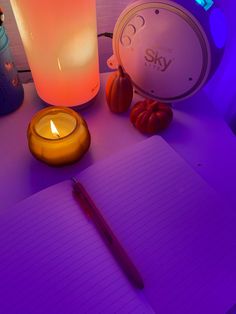 an open notebook sitting on top of a table next to a candle