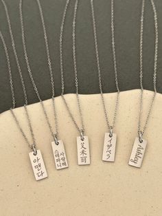 This listing is for a personalized engraved Japanese name dainty tag necklace in stainless steel. Stainless steel jewelry is strong and almost never tarnish or corrode.  The sample necklaces are engraved with Isabella in Japanese in the font #5 vertically and You are beautiful in Japanese in the font #2 in two vertical lines. If there are many characters, they will be engraved in two lines. Please check the font options in the pictures. The tag pendant is 6 mm wide and 15 mm high. The necklace is a 45 cm (17 inches) with a 5 cm (2 inches) extender chain. All orders come gift-wrapped. << How to order >> Please choose engraving side from the options. Please leave the name or word and font style number you want. If you don't choose a font, the font #5 used for the sample will be used. If you Rectangular Stainless Steel Necklaces With Engraved Text, Rectangular Stainless Steel Necklace With Engraved Text, Minimalist Stainless Steel Necklace With Engraving Option, Personalized Rectangular Spiritual Necklace, Everyday Rectangular Necklace With Engraved Text, Everyday Rectangular Necklaces With Engraved Text, Everyday Rectangular Engraved Text Necklace, Engraved Silver Rectangular Charm Necklace, Silver Engraved Rectangular Charm Necklace