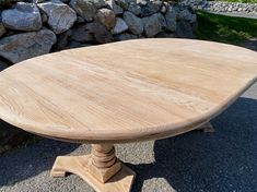 an oval wooden table sitting in front of a rock wall