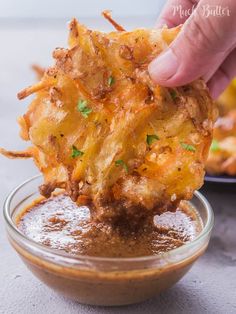 a person dipping some food into a small glass bowl filled with sauce and other foods