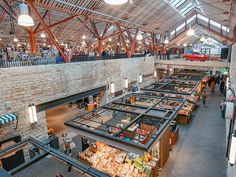 the inside of a large building with lots of tables and people walking around in it