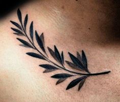 a close up of a woman's chest with a leaf tattoo on her chest