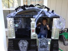 a little boy sitting in a halloween train with spider webs on it's roof