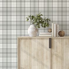 a white vase sitting on top of a wooden cabinet next to a wallpapered wall