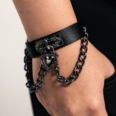 Black Leather Wristband with Heart Padlock Elevate your style with our Black Leather Wristband, measuring 8.5 inches in length and 1.75 inches in width. This piece features a stained metallic chain and a heart-shaped padlock, adding a touch of edgy elegance to your look. Designed for comfort and versatility, this wristband is not too bulky, making it perfect for daily wear. Whether you're dressing up or keeping it casual, this wristband is a standout accessory that complements any outfit. Black Rock Style Wristband As Gift, Black Punk Chain Bracelet As A Gift, Black Punk Style Chain Bracelet For Gift, Black Punk Style Chain Bracelet As Gift, Punk Style Black Chain Bracelet Gift, Alternative Style Black Bracelets As Gift, Alternative Style Black Bracelet For Gift, Alternative Style Black Bracelet Gift, Edgy Bracelet Strap Jewelry Gift