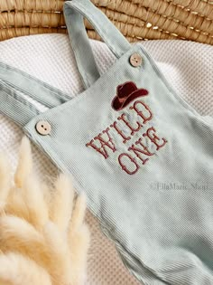 a baby's bib with the words wild one on it and a straw hat