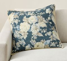 a blue floral pillow sitting on top of a white couch