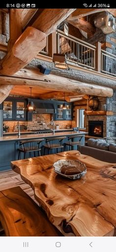 a wooden table sitting in the middle of a living room next to a kitchen and dining area