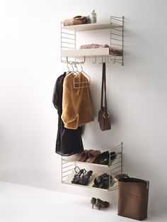 a white shelf with shoes and purses hanging from it's sides next to a wall mounted coat rack