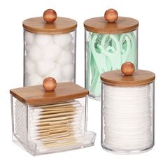 three glass containers with wooden lids and bamboo handles, one holds matches and the other holds cotton swabs