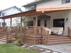 a wooden porch with steps leading up to the front door and covered patio area next to it