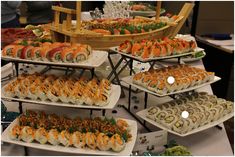 a table topped with lots of trays filled with different types of sushi and other foods