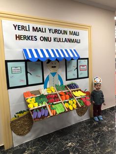 a little boy standing in front of a display of fruits and veggies for sale