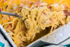 a person is holding a fork full of macaroni and cheese casserole