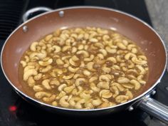 a pan filled with cashews sitting on top of a stove