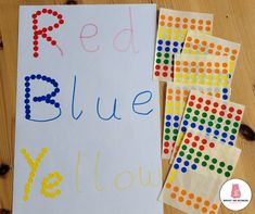 a red, blue and yellow sign sitting on top of a wooden table next to pieces of paper