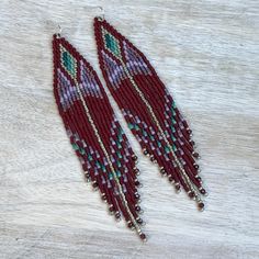 Beaded fringe earrings in burgundy/maroon and purple tones, with garnet gemstone beads at the fringe ends. Details: * Made with lightweight, glass, Delica seed beads and sterling silver  ear wires.  * Length: Drop length (including ear wire) is approximately 12 cm. Width is  2  cm.   * Packaging: Your order will arrive lovingly packaged in a gift box, wrapped with a ribbon and ready for gifting. * Please visit my Etsy shop for a full selection of my handmade jewelry: https://www.etsy.com/shop/be Burgundy Dangle Earrings, Handmade Burgundy Dangle Earrings, Bohemian Burgundy Beaded Jewelry, Purple Beaded Fringe Earrings For Festivals, Purple Beaded Fringe Jewelry For Festival, Maroon Purple, Beaded Fringe Earrings, Purple Tones, Bead Embroidery Patterns