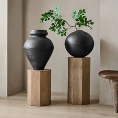 two black vases sitting on top of wooden blocks