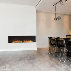 a dining room table with black chairs and a fire place in the wall behind it