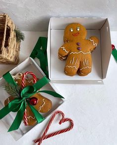 two gingerbreads in boxes with green ribbon and candy canes on the table