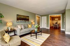 a living room filled with furniture and a painting on the wall above it's doorway