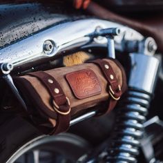 a close up of a motorcycle handlebar with a leather bag on it's side