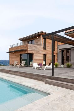 a house with a pool in front of it and some lounge chairs around the pool