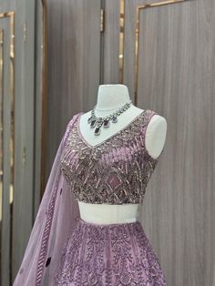 Our stunning Net Fabric Party Wear Lehenga in striking purple is perfect for making a bold statement at any special occasion, featuring intricate embroidery work in gold and silver threads. Purple Wedding Gown With Intricate Embroidery, Elegant Semi-stitched Purple Sets, Elegant Purple Sets With Intricate Embroidery, Elegant Lavender Sets For Festive Occasions, Elegant Lavender Festive Sets, Elegant Festive Lavender Sets, Lavender Sharara With Intricate Embroidery For Wedding, Fitted Silver Lehenga For Eid, Lavender Embroidered Sharara For Wedding