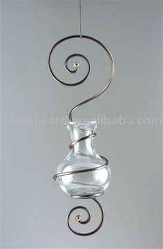 a glass vase hanging from a metal wire with a spiral design on the top and bottom