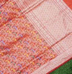 an orange and red saree laying on top of green grass