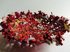 a bowl that is made out of red and white beads, with other objects in it