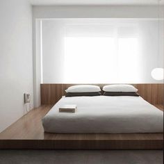 a bed with white sheets and pillows in a room next to a wall mounted light