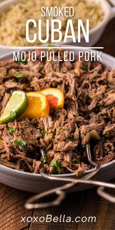 a bowl filled with pulled pork and garnished with cilantro, limes, and orange slices