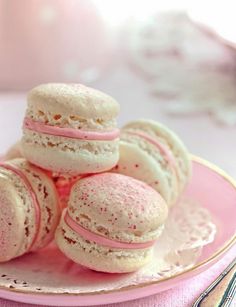 pink and white macaroons sitting on a plate