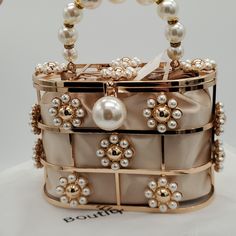 This Beautiful Handbag Is Brand New And Has Never Been Used. I Just Love It! It Is A Fully Functional Bag / Purse It Has Magnetic Closure And A Beautiful Satiny Sack With Pearl Detailed Draw Strings To Keep Your Belongings Privatly Together Inside It Is A Gorgeous Statement Piece To Any Gown Or Party Or Wedding Dress It Can Also Be Used As A Statement Piece In Any Room. It Is Truly Gorgeous And I Hate To Part With It I Simply Have Never Used It And I Am A Bit Of A Pack Rat. Measurements Are 7.07 In Length 3.14 Depth 5.11 Height Happy Poshing! Party Bucket Bag With Gold-tone Hardware, Beige Bags With Pearl Handle For Spring, Spring Evening Rectangular Bags, Cream Bags With Pearl Handle For Spring, Gold Top Handle Bag For Spring, Gold Bag With Detachable Strap For Spring, Spring Gold Clutch Bag, Gold Spring Clutch Bag, Gold Clutch Bag For Spring