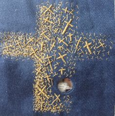 a cross made out of yellow sprinkles on a blue piece of cloth