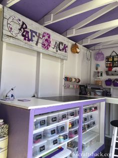 the interior of a craft shop with purple walls and white shelves filled with crafts supplies