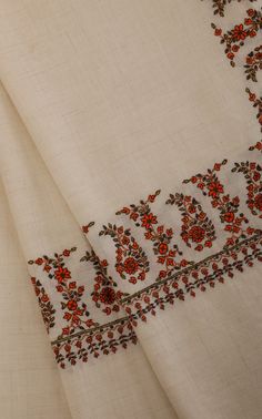 an embroidered white cloth with red flowers on it