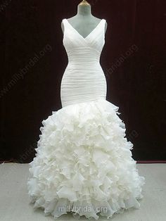 a white wedding dress is displayed on a mannequin stand in front of a black backdrop