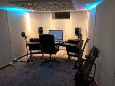 a room with guitars, laptop and other musical equipment in the corner on carpeted flooring