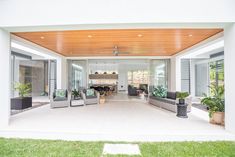 a large open living room with couches and plants on the outside wall, surrounded by greenery