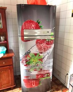 a refrigerator that has strawberries on the side and water splashing out of it