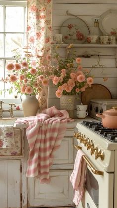 a kitchen with pink flowers on the window sill and an old stove top oven